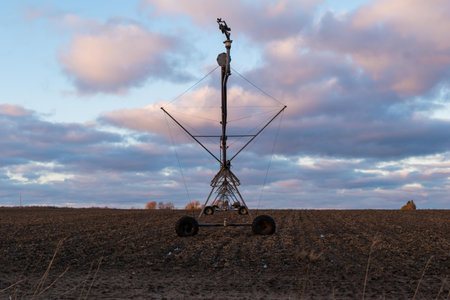 Irrigation equipment on a harvested field at sunset from the end point of view.