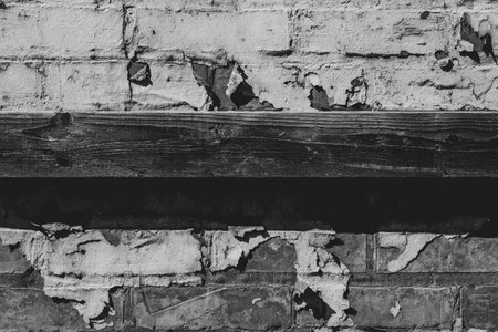 Weathered brick wall with a strip of wood and chipped paint