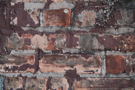 Textured brick wall with chipped and weathered red paint