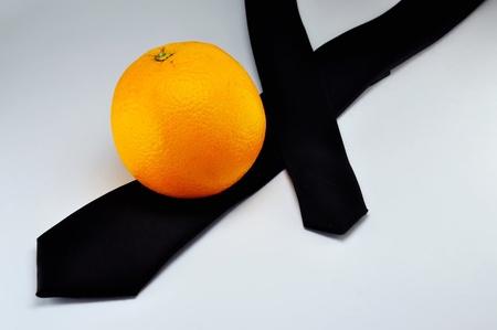 The orange lays on a black Necktie; time to make a dinner on workの写真素材
