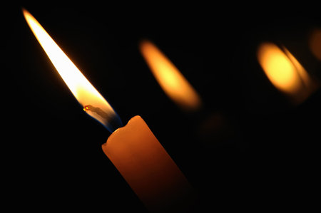 A burning candle in the church on a dark background