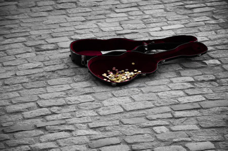 Guitar case full of coins on gray tilesの写真素材