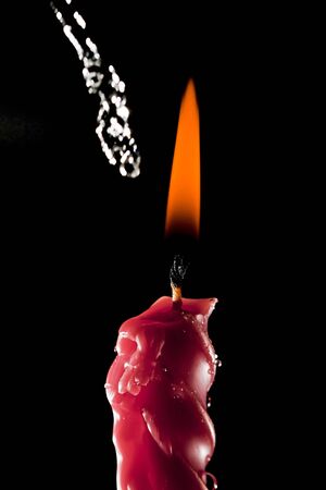 High speed shot for water being sprinkled over a lighted red candle. Part of series.の写真素材