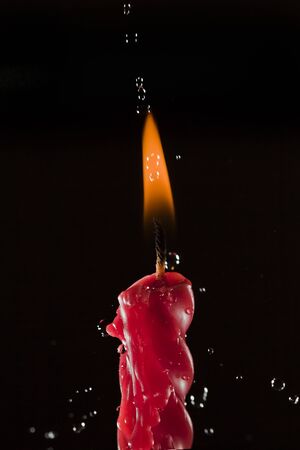 High speed shot for water being sprinkled over a lighted red candle. Part of series.の写真素材