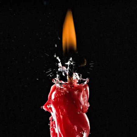 High speed shot for water being sprinkled over a lighted red candle. Part of series.の写真素材