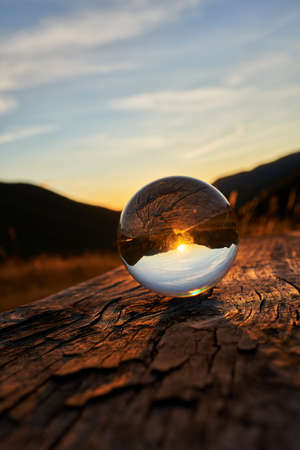 Sunset in the mountains of southern Asturias Spain with a crystal ball that flips everything on top of a vertical wooden benchの写真素材