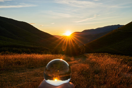 Sunset in the mountains of southern Asturias in Spain with a hand holding a crystal ball