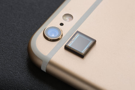 A piece of CMOS placed next to a mobile phone camera.