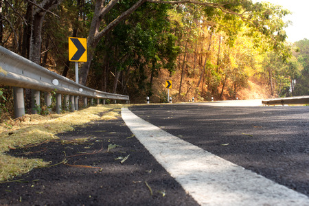 Curved road,trees and grass on roadside.Empty asphalt road running through forest.の写真素材