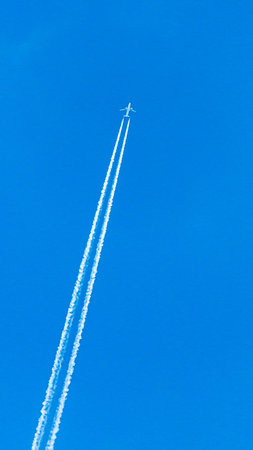 Two engined airplane during flight with condensation trails