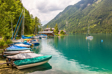 Sailing and paddle boats on boat pier at east shore of Weissensee in Austria