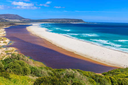 Photo of Noordhoek Beach near Cape Town from Chapmans Peak Drive in blue skies with a sandbank between the sea and brown river water photographed in South Africa in September 2013の写真素材