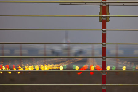 Picture of a security fence at an airport with a runway and landing plane in the background