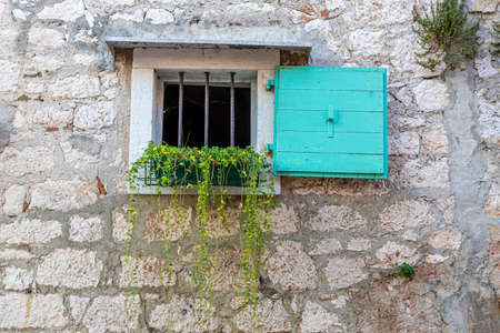 Closeup of an old natural stone wall with a small window typical texture as a background templateの写真素材
