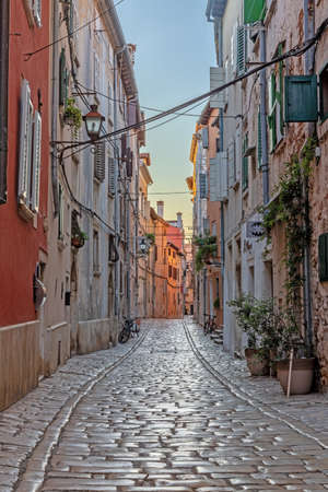 Scene of a cobblestoned street in the historic center of Rovinj in Croatia during sunrise in summerの写真素材
