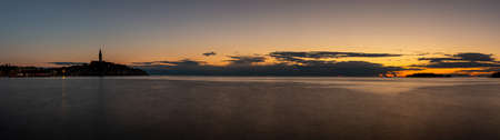 View to the historic center of Rovinj during sunset with water reflections and nice cloud formations in summerの写真素材