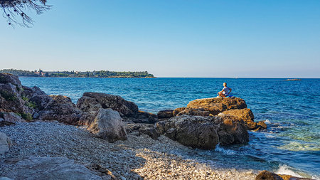 Picture of a woman doing yoga on a rock by the sea in the evening sun