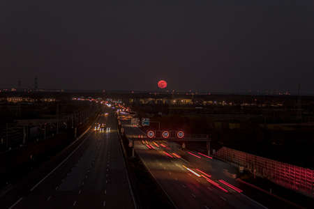 Image of Pink Moon rising over a German highway in April 2021 in evening timeの写真素材