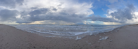 Panoramic winter image of Skallingen beach in Denmark with surf and impressive cloud formationsの写真素材