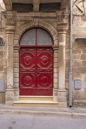 Image of a red entrance door to a residential building with an antique faÃ§ade in daylightの写真素材