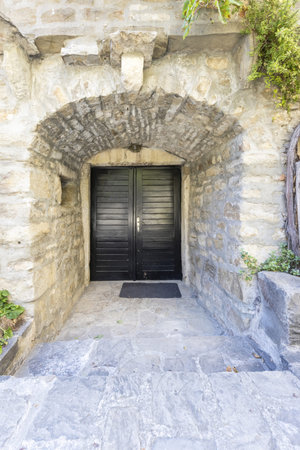 Image of a red entrance door to a residential building with an antique faÃ§ade in daylight