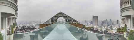 Panoramic picture of a walkway on the roof terrace of a high-rise building in Bangkok during the day