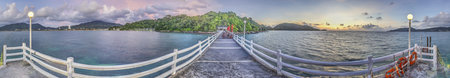 Panoramic picture over a jetty with wooden railing over the tropical sea near Patong on Phuket in...