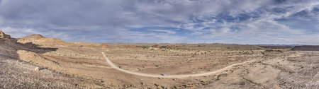 Panoramic drone picture over a gravel road near Fish River Canyon in southern Namibia under a blue sky in summerの写真素材