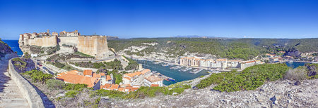 Historic Bonifacio on Corsica's dramatic limestone cliffs against a clear blue Mediterranean sea and sky in summerの写真素材