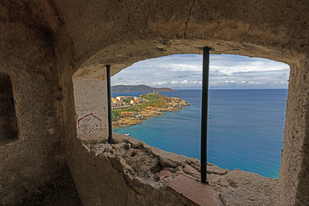 View through a fortress window overlooking a scenic bay and coastal village, capturing history...