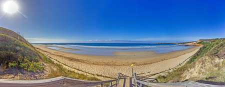 Wide sandy beach and calm ocean waves with clear blue skies, Great Ocean Road during daytime