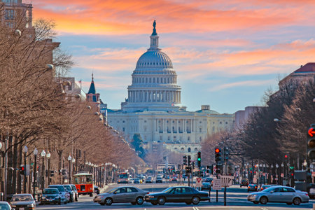 The US Capitol Dome overlooking a busy street with traffic under a colorful sunset in Washington DC during sunsetの写真素材