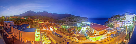 Nighttime coastal view of Cala Sant Vicenc with illuminated streets in summerの写真素材