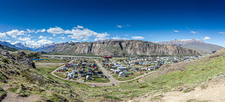 View of El Chalten village surrounded by rocky cliffs and snowy mountain peaks in Patagonia during daytimeの写真素材