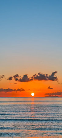 Beautiful sunrise over the ocean with calm waves and golden reflectionsの写真素材