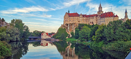 Majestic Sigmaringen Castle reflected in the calm river under a blue sky in evening lightの写真素材