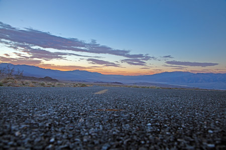 Scenic desert road at sunset with colorful clouds and mountain backdrop in winter
