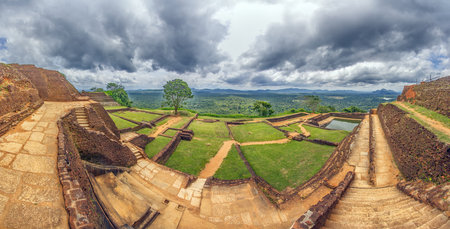 Panorama of ancient ruins on Sigiriya Rock with green landscape and stormy clouds during daytimeの写真素材