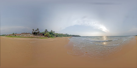 Resort beach with ocean waves and sun rays breaking through clouds in eveningの写真素材