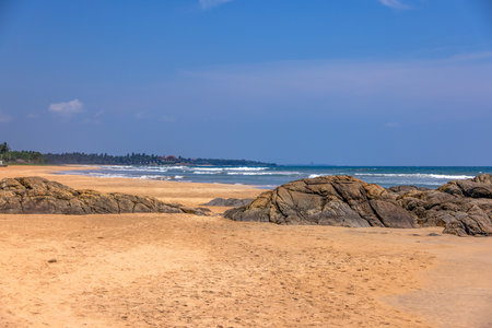 Sunny tropical beach with rocks and turquoise ocean in Sri Lanka in summerの写真素材