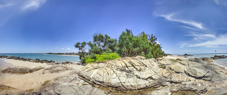 Sunny tropical beach with rocks and turquoise ocean in Sri Lanka in summer
