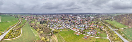 Aerial view of Bad Arolsen with residential area, fields and forest under cloudy sky during daytimeの写真素材