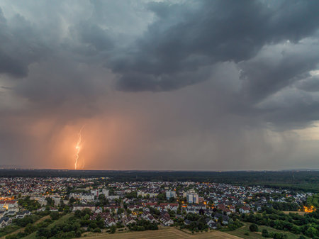 Lightning bolt striking near Moerfelden Walldorf over city buildings and dramatic storm clouds