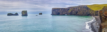 View of sea stacks and cliffs along Reynisfjara black sand beach Iceland with waves and ocean