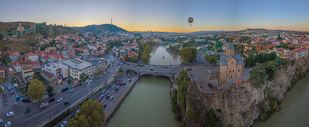 Aerial panorama of Tbilisi Georgia with Kura river Metekhi church and city skyline at sunset