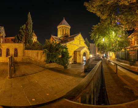 Night view of small Orthodox church and historic buildings in old town Tbilisi Georgia with warm...