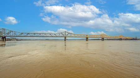 View from the riverbank showing the parallel bridges over the Ohio River connecting Kentucky and Indianaの写真素材