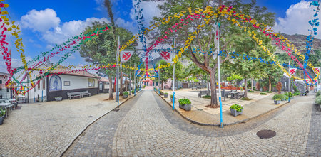 Colorful decorated street with Sao Jorge church on Madeira island in Portugal under blue skyの写真素材