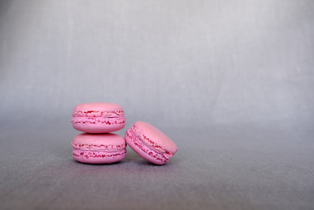 Stack of delicious french pink strawberry macarons on grey background. Tasty colorful sandwich cookies, copy spaceの写真素材