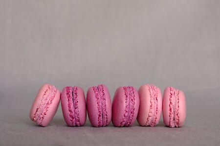 Fresh delicious pink and purple french macarons on grey background. Space for text. Colorful meringue based cookies, fruity flavoursの写真素材
